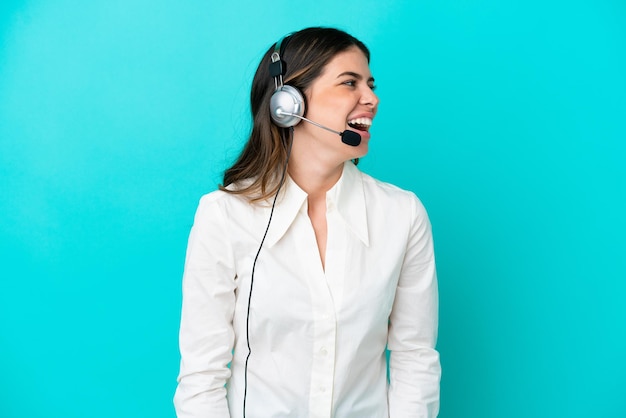 Telemarketer Donna italiana che lavora con un auricolare isolato su sfondo blu che ride in posizione laterale