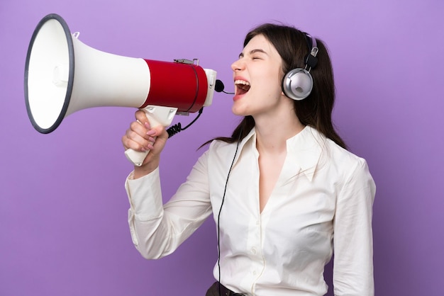 Telemarketer Donna russa che lavora con un auricolare isolato su sfondo viola che grida attraverso un megafono