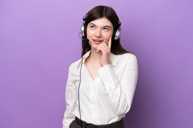 Telemarketer Donna russa che lavora con un auricolare isolato su sfondo viola pensando a un'idea mentre guarda in alto