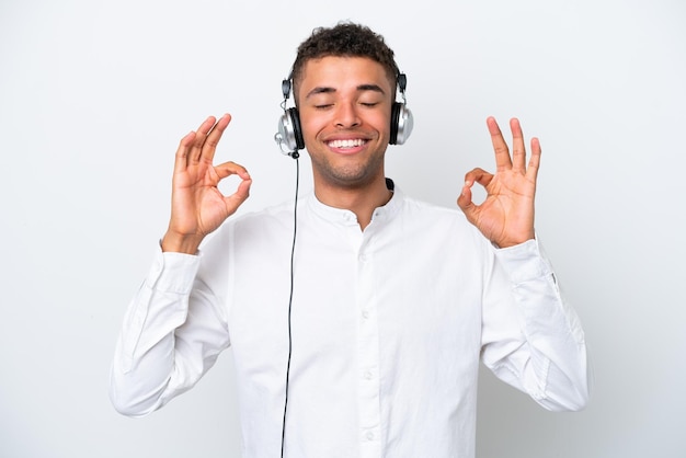 Telemarketer Uomo brasiliano che lavora con un auricolare isolato su sfondo bianco in posa zen