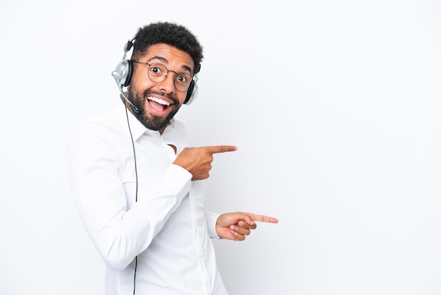 Telemarketer Uomo brasiliano che lavora con un auricolare isolato su sfondo bianco sorpreso e indicando il lato