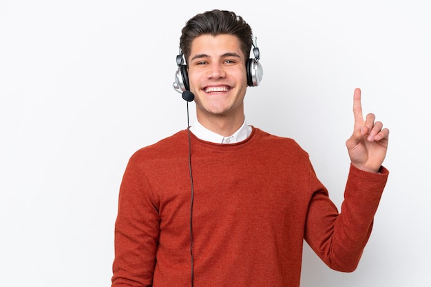 Telemarketer uomo caucasico che lavora con un auricolare isolato su sfondo bianco che mostra e alza un dito in segno di meglio