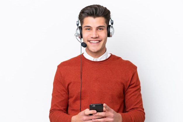 Telemarketer uomo caucasico che lavora con un auricolare isolato su sfondo bianco inviando un messaggio con il cellulare