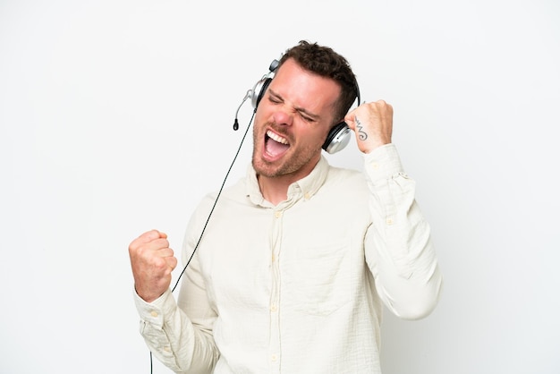 Telemarketer uomo caucasico che lavora con un auricolare isolato su sfondo bianco per celebrare una vittoria