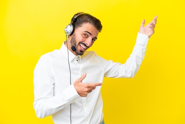 Telemarketer uomo caucasico che lavora con un auricolare isolato su sfondo giallo facendo un gesto di chitarra