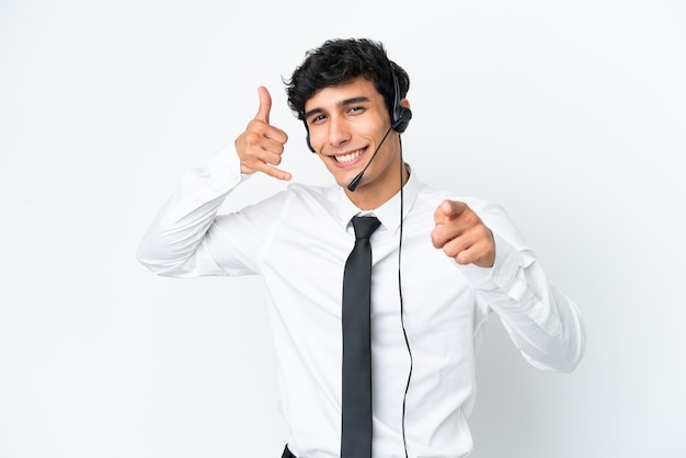 Telemarketer uomo che lavora con un auricolare isolato su sfondo bianco che fa il gesto del telefono e indica la parte anteriore