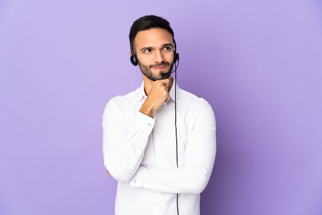 Telemarketer uomo che lavora con un auricolare isolato su sfondo viola con dubbi e pensieri