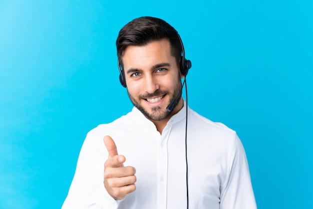 Telemarketer uomo che lavora con un auricolare sopra il dito punti blu a voi