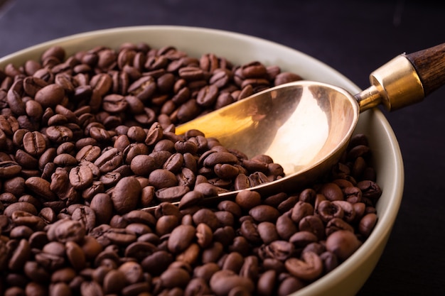 Tema del caffè. Piatto con chicchi di caffè sul tavolo di legno nero.