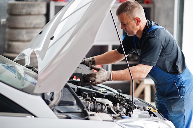 Tema di riparazione e manutenzione dell'auto Meccanico in uniforme che lavora nel motore di controllo del servizio automatico