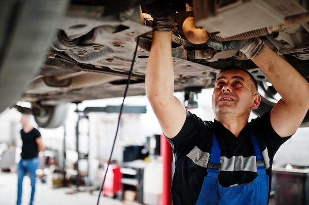 Tema di riparazione e manutenzione dell'auto. Meccanico in uniforme che lavora nel servizio auto.