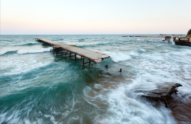 Tempesta di mare serale e molo in rovina