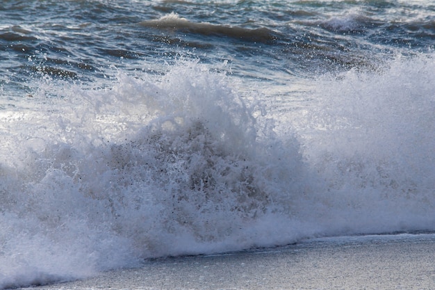 Tempesta sul mare nei raggi delle grandi onde del tramonto, spray.