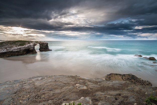 tempesta sulla spiaggia delle cattedrali con la pioggia all&#39;orizzonte