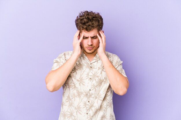 Tempie commoventi del giovane uomo caucasico dei capelli ricci biondi e avere mal di testa.