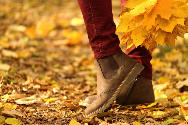 Tempo d'autunno. Gambe femminili in stivali scamosciati marroni su foglie gialle. Scarpe autunnali alla moda