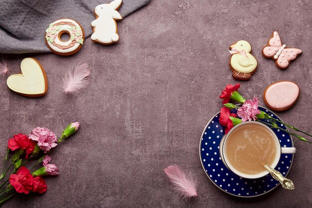 Tempo di caffè estetico di Pasqua Biscotti smaltati tazza di caffè piume aster fiori posati piatti Primavera sfondo elegante con spazio per la copia