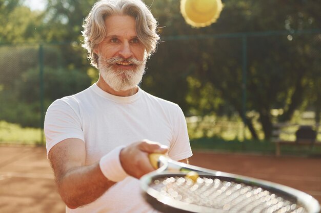 Tempo di formazione Uomo moderno ed elegante con racchetta all'aperto sul campo da tennis durante il giorno