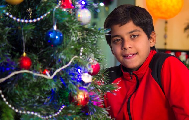 Tempo di Natale Un ragazzo sorridente vicino all'albero di Natale addobbato