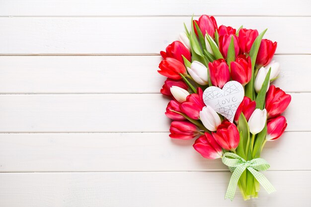 Tempo di primavera. Bouquet di tulipani rossi su fondo di legno bianco.