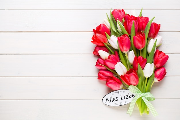 Tempo di primavera. Bouquet di tulipani rossi su fondo di legno bianco.