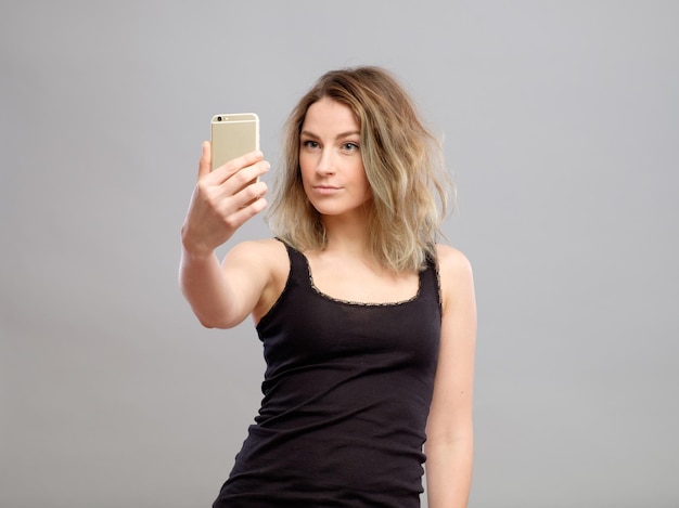 Tempo di selfie Giovani donne gioiose che fanno selfie con il suo smartphone isolato su grigio