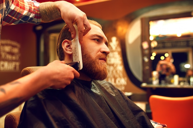 È tempo di una nuova pettinatura. Il giovane barbuto bello è venuto dal barbiere per un taglio di capelli. stile hipster. il concetto di moda e bellezza.