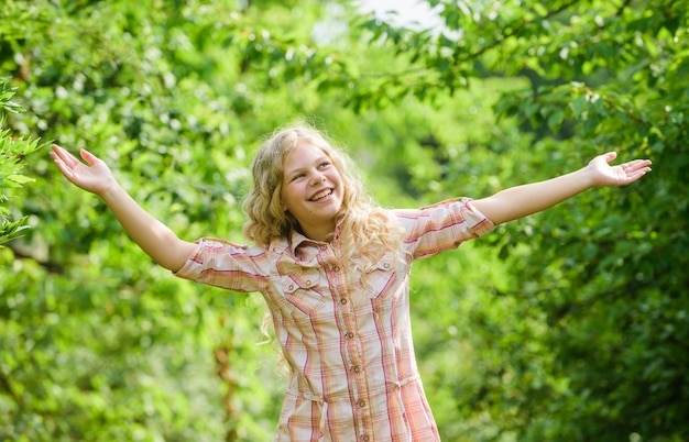 Tempo felice bellezza e moda capelli ricci biondi lunghi bambina nella foresta verde vacanze estive giorno dei bambini bambina felice con capelli lunghi sani capelli salute e cura parrucchiere