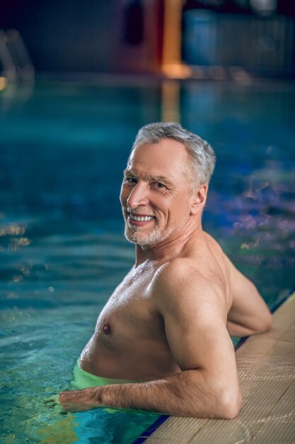 Tempo in piscina. Un bell'uomo di mezza età che nuota in una piscina e sembra contento