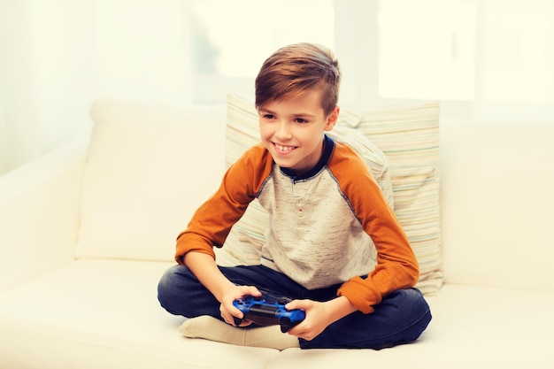 tempo libero, bambini, tecnologia e concetto di persone - ragazzo sorridente con joystick che gioca a videogiochi a casa
