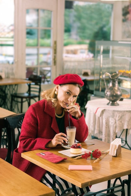 Tempo libero. Bella donna alla moda che si sente semplicemente sollevata e fantastica trascorrendo il tempo libero in una bella pasticceria