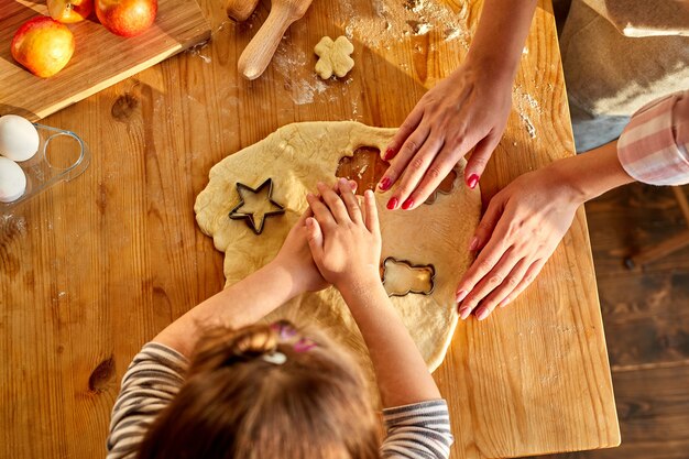 Tempo libero in famiglia in cucina. madre amichevole che insegna alla figlia come fare i biscotti con la pasta