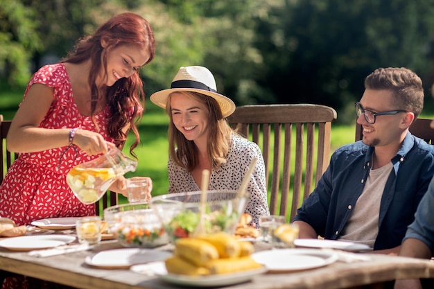 tempo libero, vacanze, mangiare, persone e concetto di cibo - amici felici che cenano alla festa estiva in giardino