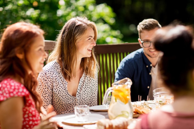 tempo libero, vacanze, mangiare, persone e concetto di cibo - amici felici che cenano alla festa estiva in giardino