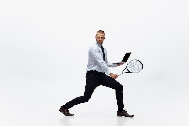 Tempo per il movimento. L'uomo in abiti da ufficio gioca a tennis isolato su sfondo bianco per studio.