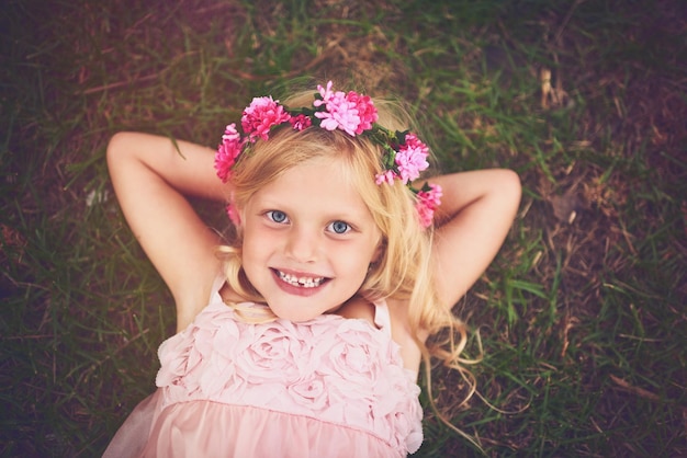 Tempo per rilassarsi Inquadratura di una bambina felice che guarda la telecamera sdraiata sull'erba e si rilassa all'aperto nella natura