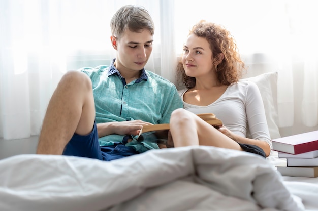 Tempo romantico Le coppie caucasiche abbracciano e leggono il libro nel letto.