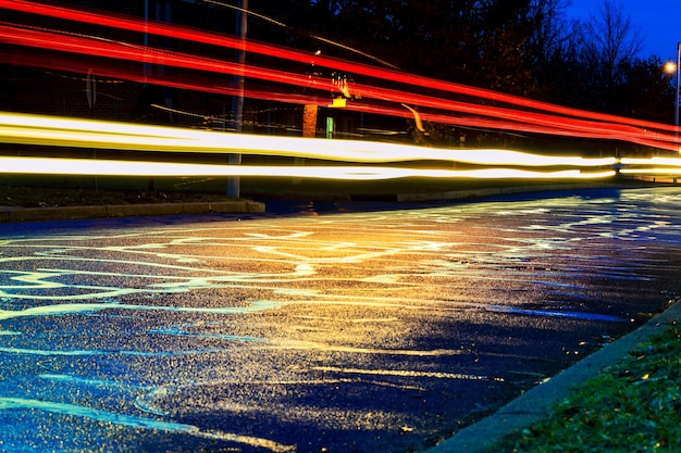 Temporale nella luce notturna della grande città dalle vetrine dei negozi riflessa sulla strada su cui transitano le auto...