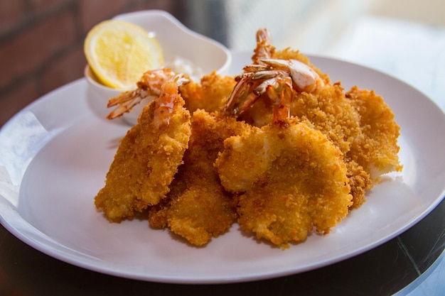 TEMPURA DI GAMBERI con fetta di lime servita in un piatto isolato sulla vista laterale del tavolo