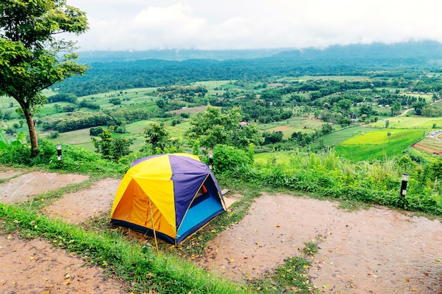 Tenda da campeggio che si trova nel punto più alto di un'alta montagna con lo sfondo di cielo e montagne.