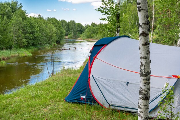 Tenda da campeggio in una foresta vicino al fiume. Tenda turistica nella foresta. sfondo turistico. Turismo naturalistico, stile di vita e concetto di vacanza in campeggio