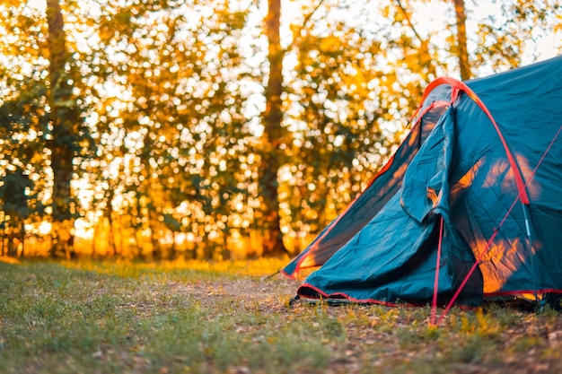 Tenda da campeggio nella foresta con tramonto e uno splendido scenario naturale sfocato Alberi e raggi solari