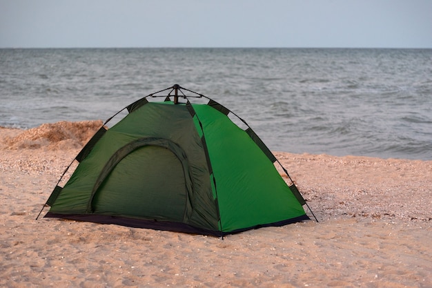 Tenda da campeggio verde sulla spiaggia contro il mare