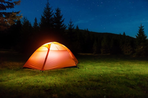 Tenda illuminata nella foresta notturna