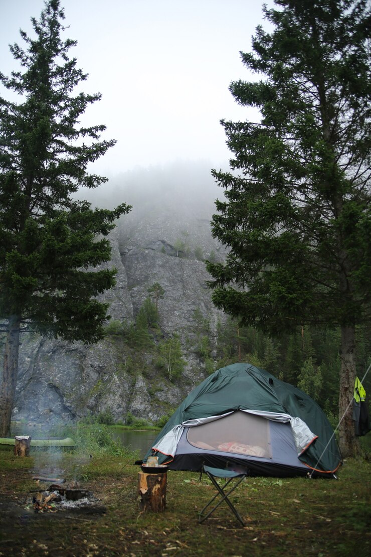 Tenda sulla riva del fiume contro le rocce nella nebbia