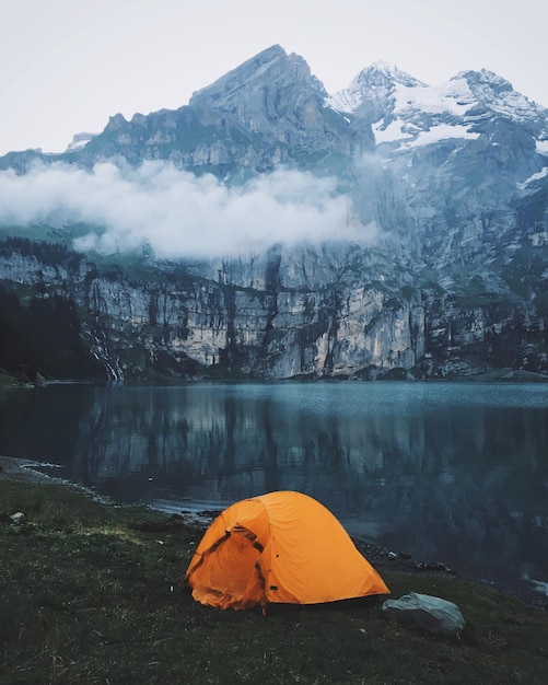 Tenda sulla riva del lago di Oeschinen contro le montagne rocciose delle Alpi svizzere