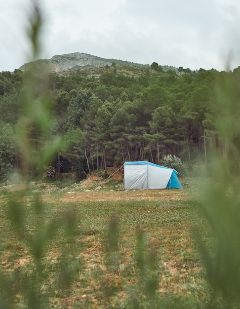 Tenda sulla riva di un lago con la foresta e le montagne