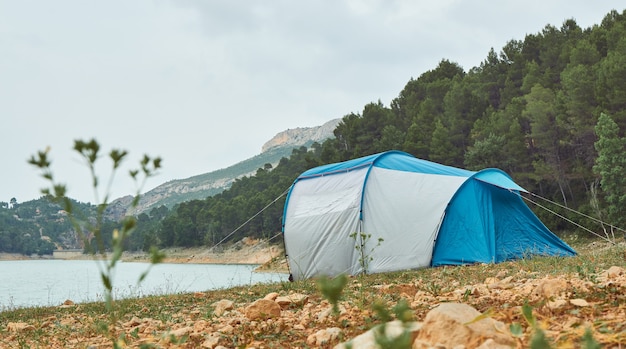 Tenda sulla riva di un lago con la foresta e le montagne