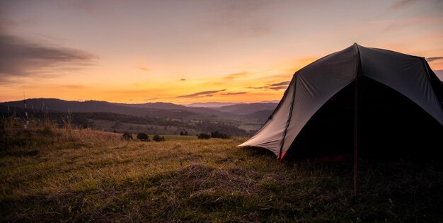 Tenda turistica in montagna sotto il drammatico cielo serale Tramonto colorato in montagna Concetto di viaggio in campeggio Viaggiatori che si godono la vacanza alternativa di vantaggio