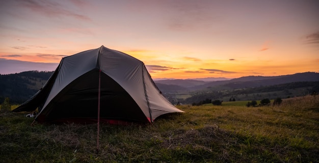 Tenda turistica in montagna sotto il drammatico cielo serale Tramonto colorato in montagna Concetto di viaggio in campeggio Viaggiatori che si godono la vacanza alternativa di vantaggio